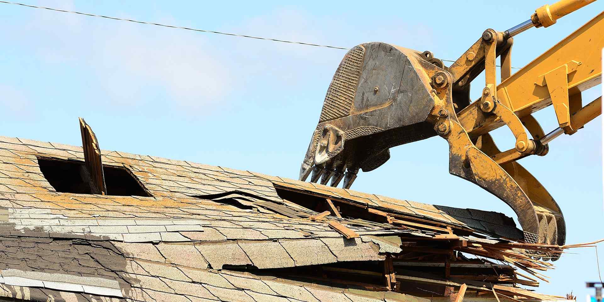 A construction machine demolishing the roof of a building.