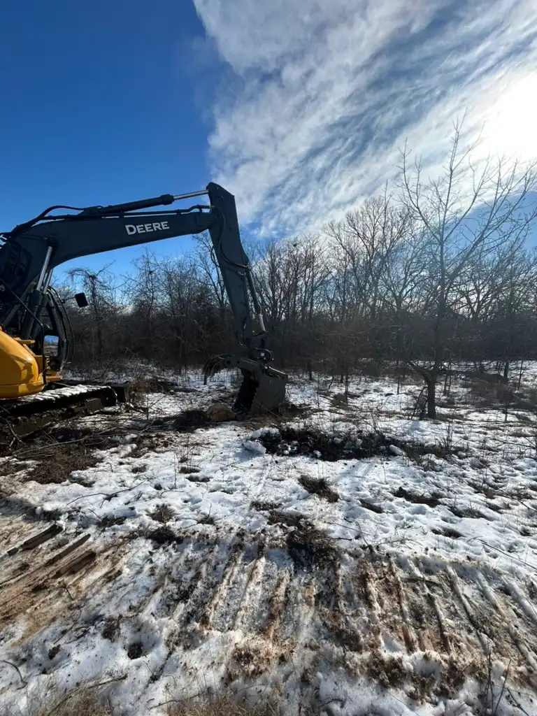 A large excavator parked on a snowy landscape, showcasing its tracks and machinery against a winter backdrop.
